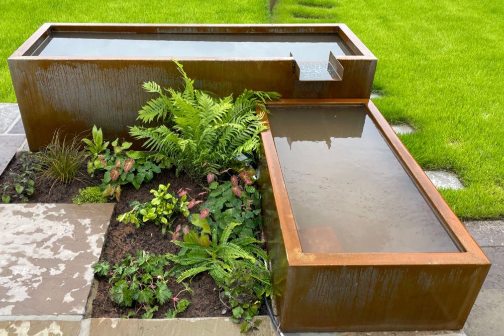 Modern outdoor Corten steel pond water feature with plants and a stone pathway