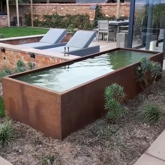 Rectangular pool with rusted corten metal edges in a garden setting