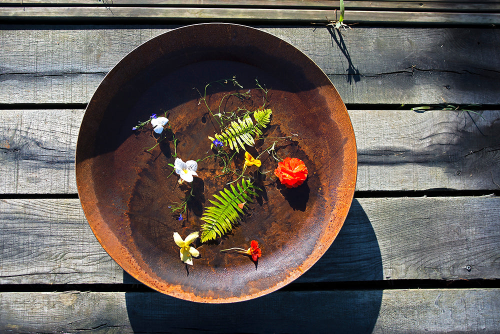 Rustic Corten steel bowl with flowers on a wooden table