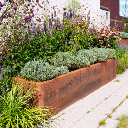 Decorative corten metal planter with plants and flowers in a garden setting.