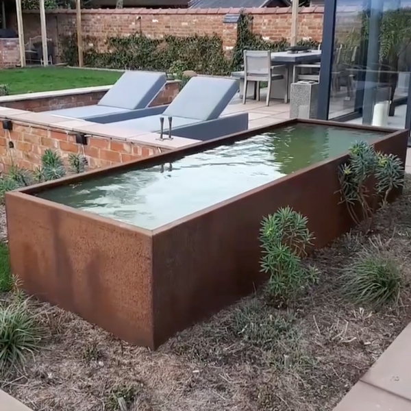 Rectangular rusted corten steel pond with exposed metal edges in a garden setting